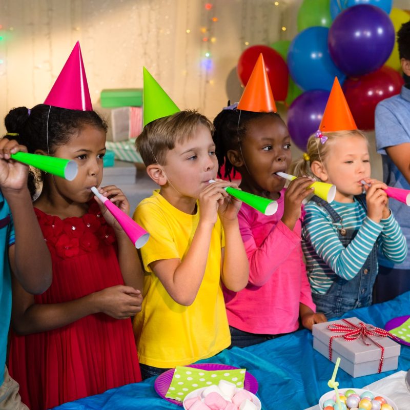Playful children blowing party horns