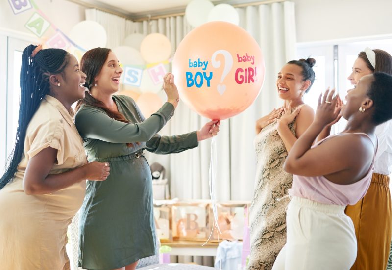 Shot of a group of women about to pop a balloon for a gender reveal during a baby shower